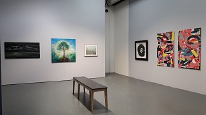 A view of the OPEN exhibition showing 4 paintings and two screen print collages. A bench is placed in the middle of the room.